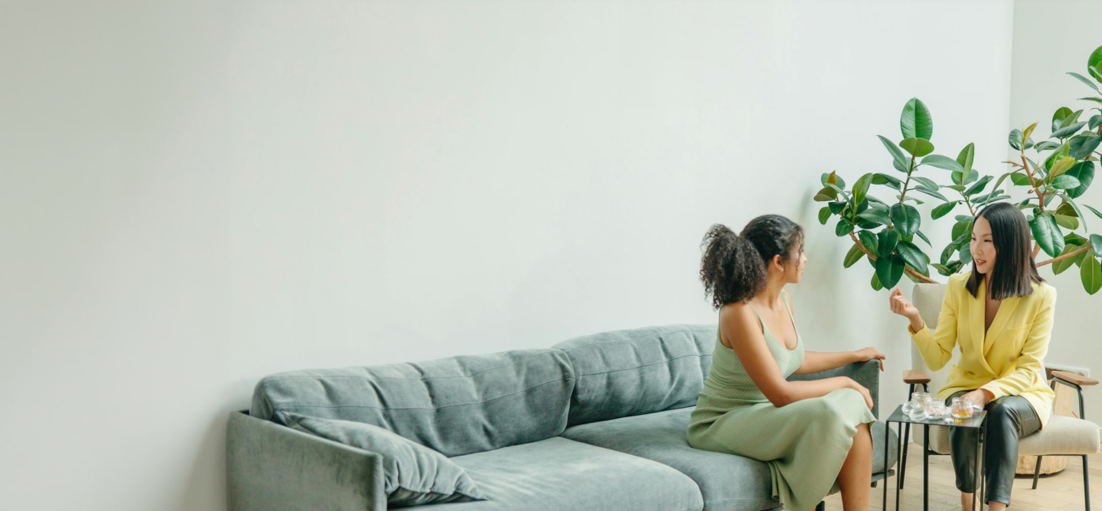 A person sitting quietly in a calm, plant-filled consulting space