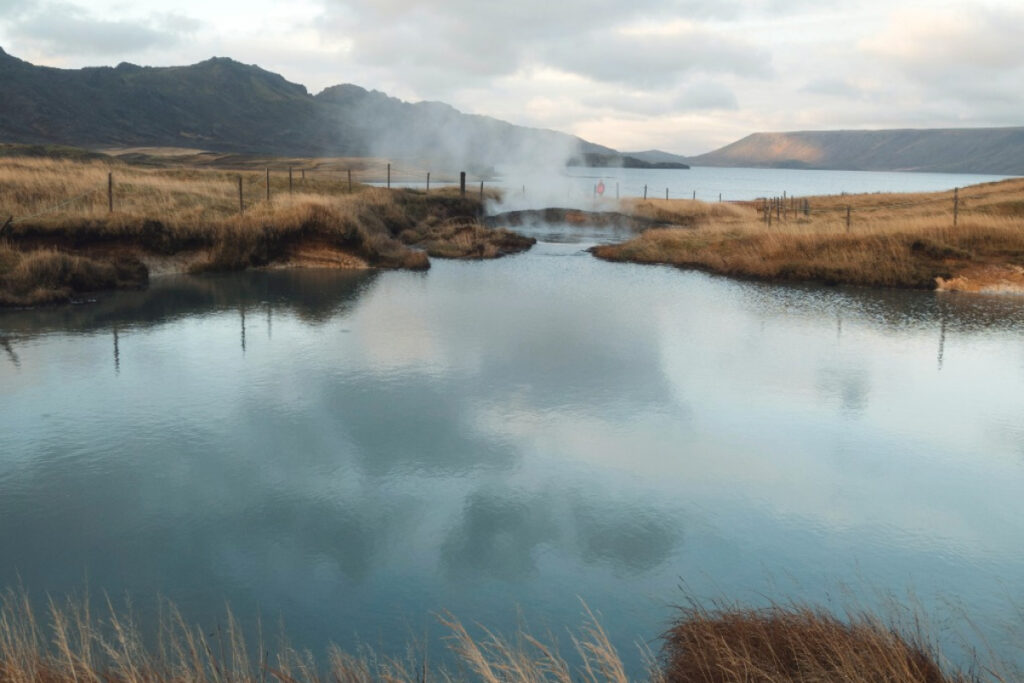 A calm river winding through grassland under a soft, cloudy sky