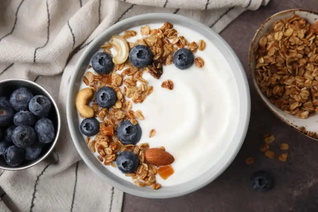Bowl of yoghurt topped with blueberries, granola, nuts and seeds