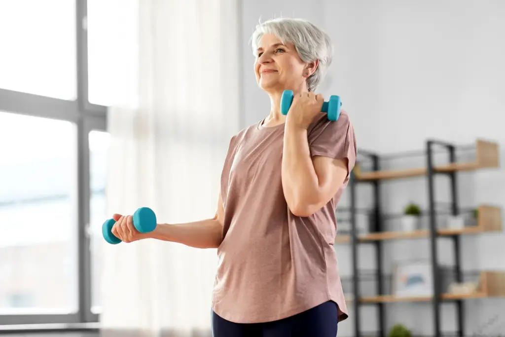 An older woman lifting a small hand weight in a bright living room